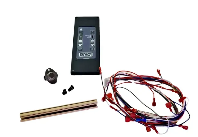 Black electronic device, coiled red-and-black wires, small black parts, and a wooden ruler on white background