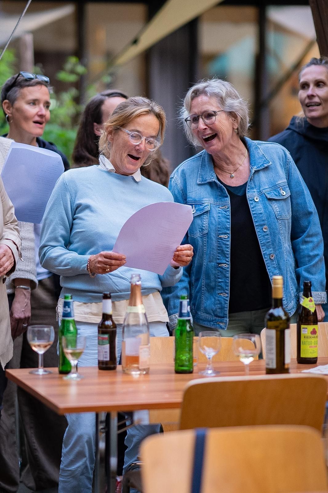 Mehrere weiblich gelesen Personen singen gelöst und fröhlich zusammen.