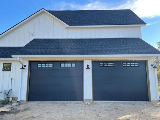 Two gray garage doors on a white two-story house exterior