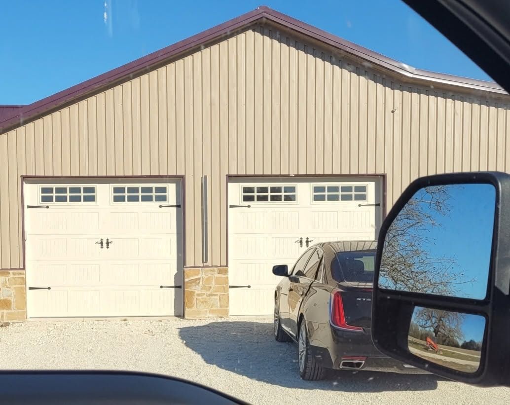 Two-car garage with beige siding, one truck parked in front, seen from inside a vehicle