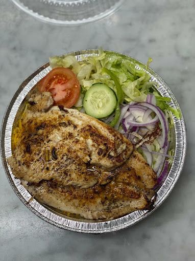 Grilled chicken with salad and tomato on a foil plate.
