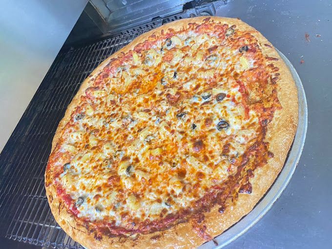 Oval pizza with melted cheese, tomato sauce, and olives on a metal pan.