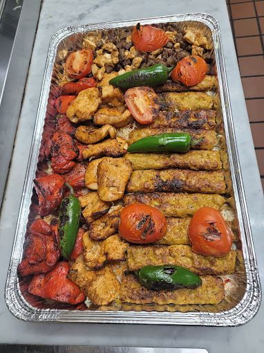 Tray of grilled chicken, kebabs, tomatoes, and peppers.