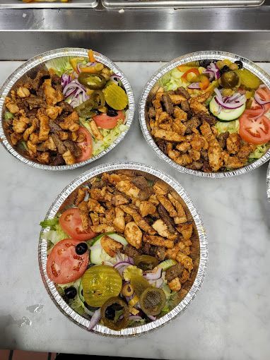 Three aluminum plates of food: chicken and beef with salad and toppings.