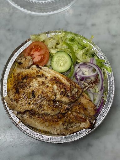 Grilled chicken with salad, tomato, cucumber, and onion in a foil container.