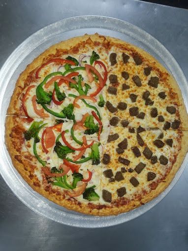 Pizza split in half with vegetables and sausage on a metal tray.