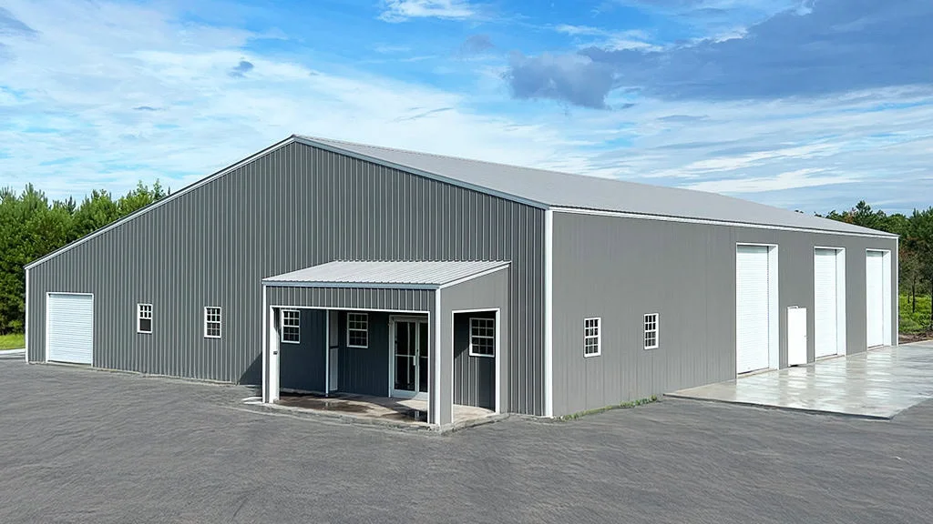 Gray metal building with a covered entrance and large garage doors under a blue sky.