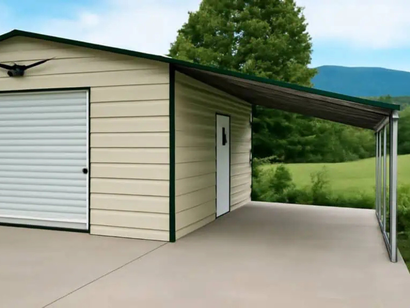 Beige metal garage with a green-trimmed awning, door, and a concrete pad; set in a grassy field.