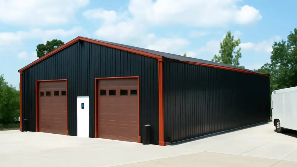 A modern dark gray metal building with open bays, housing vehicles, in a field at dusk.
