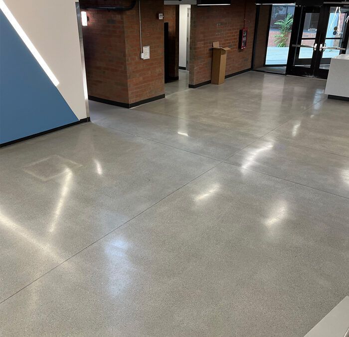 Empty lobby with polished gray floor, brick walls, and glass entrance doors