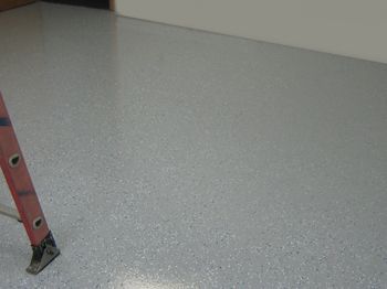 Red ladder on a gray speckled floor in a plain room