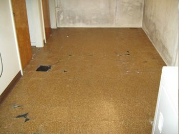 Empty brown hallway with worn flooring and beige walls