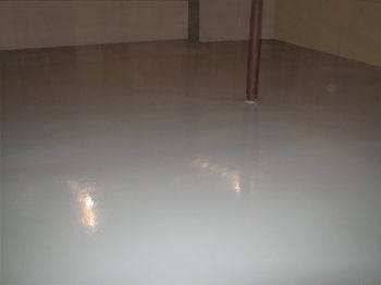 Empty white floor with reflections and a single vertical pole in the corner.