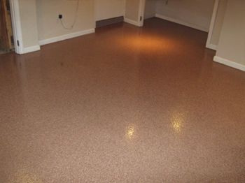Empty room with glossy brown speckled floor and white walls, lit by a ceiling light.