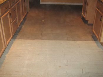 Kitchen floor with a light-colored threshold and darker wood cabinets on both sides
