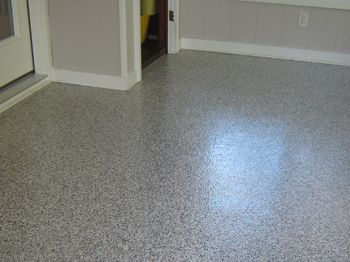 Empty speckled gray floor in a room with a doorway and wall trim