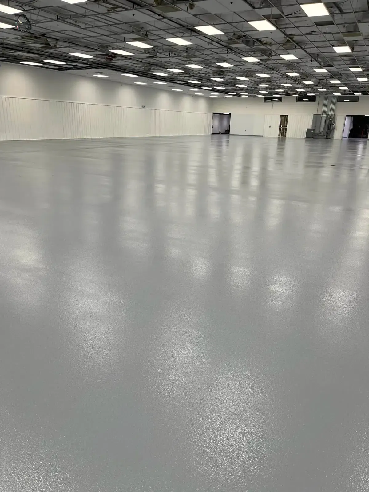 Empty indoor convention hall with a glossy gray floor and rows of ceiling lights