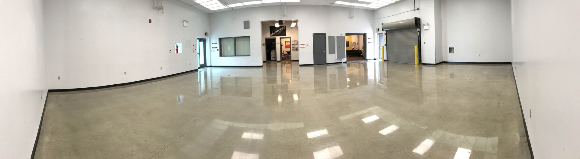 Empty indoor hallway with glossy floor, white walls, and windows at the far end.