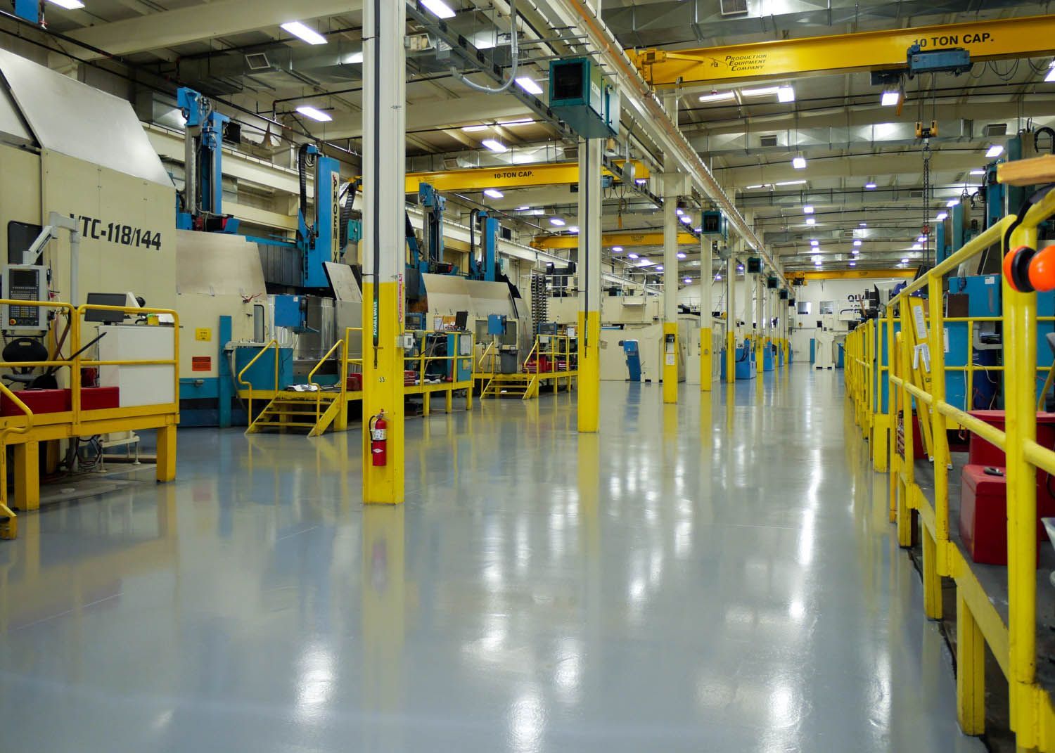 Bright factory interior with yellow machinery, blue equipment, and a polished concrete floor
