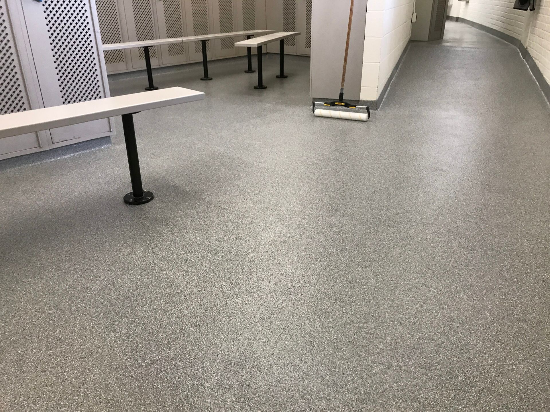 Empty hallway with speckled floor, benches, and a curved wall.
