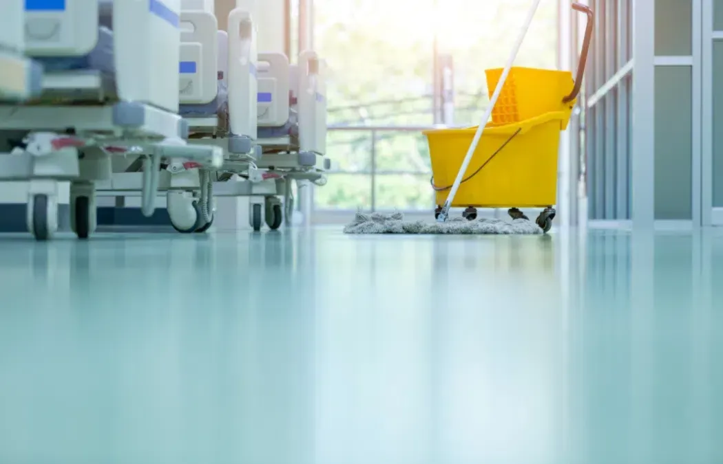 Hospital corridor with beds and a bright yellow mop bucket on a shiny floor
