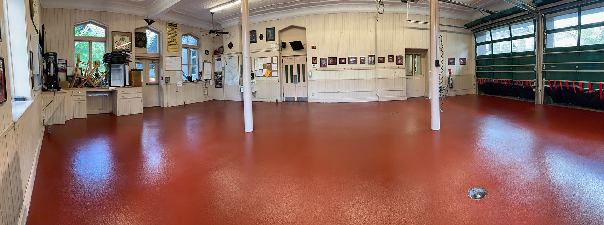 Empty indoor hall with red floor, white pillars, and mirrored walls, lit by warm overhead lights