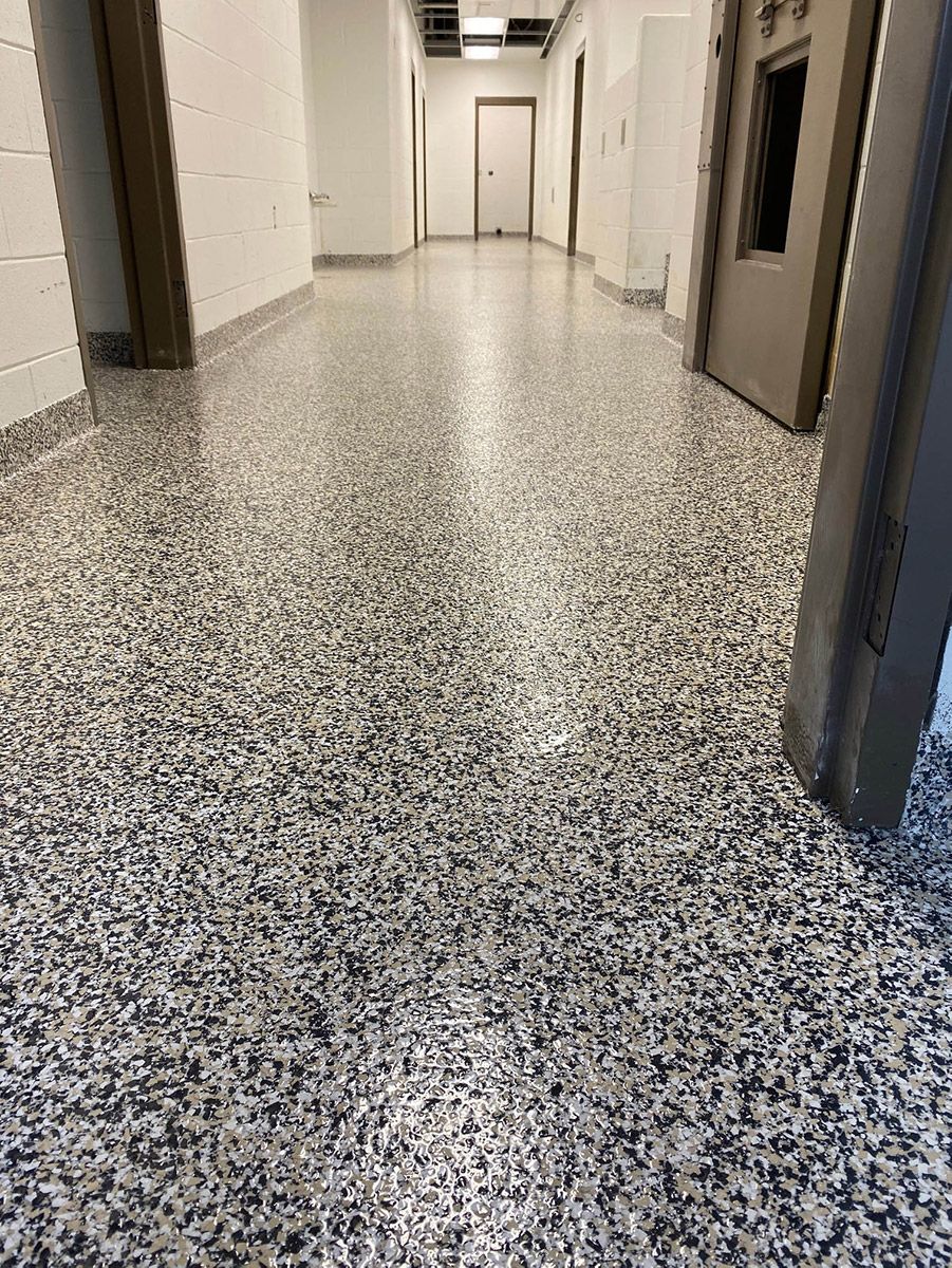 Empty hallway with speckled flooring and closed doors on both sides