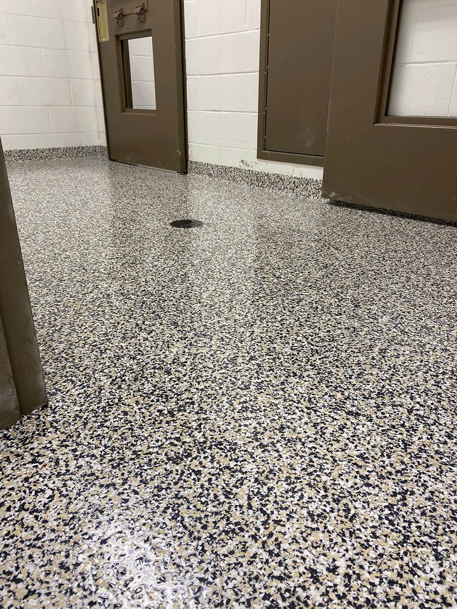 Hallway with speckled terrazzo floor and brown doors on white cinderblock walls