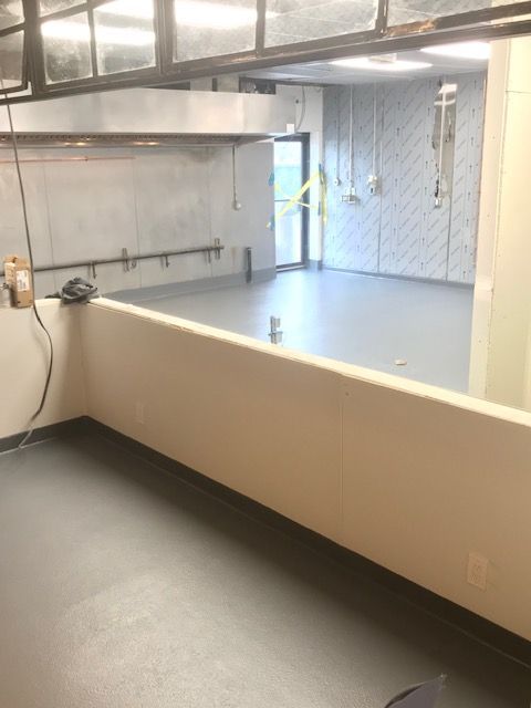 Empty industrial kitchen with stainless steel counters, sink, and tiled walls