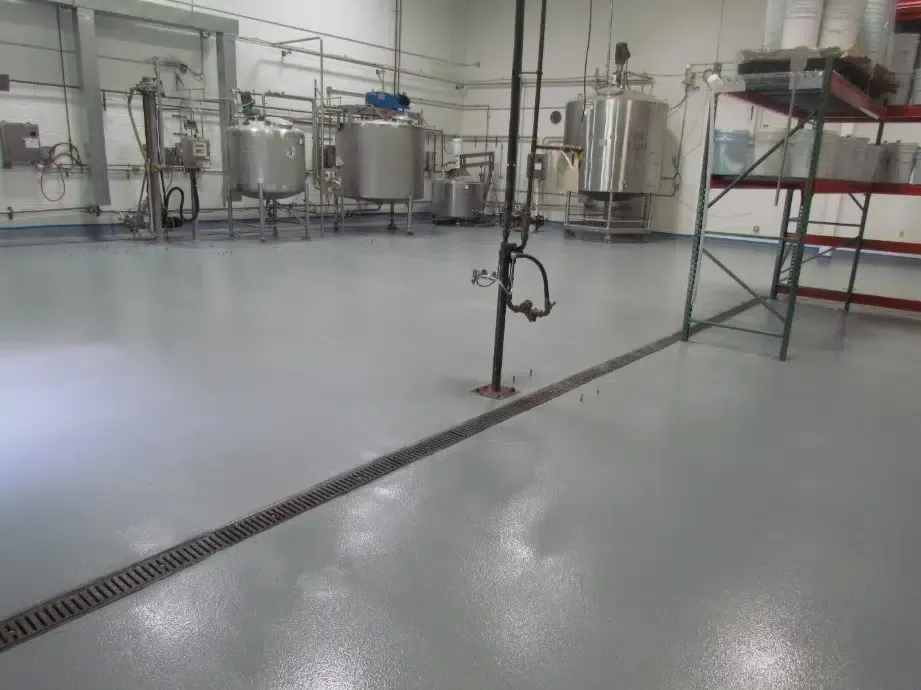 Industrial facility with stainless steel tanks, piping, and a floor drain in a clean processing room
