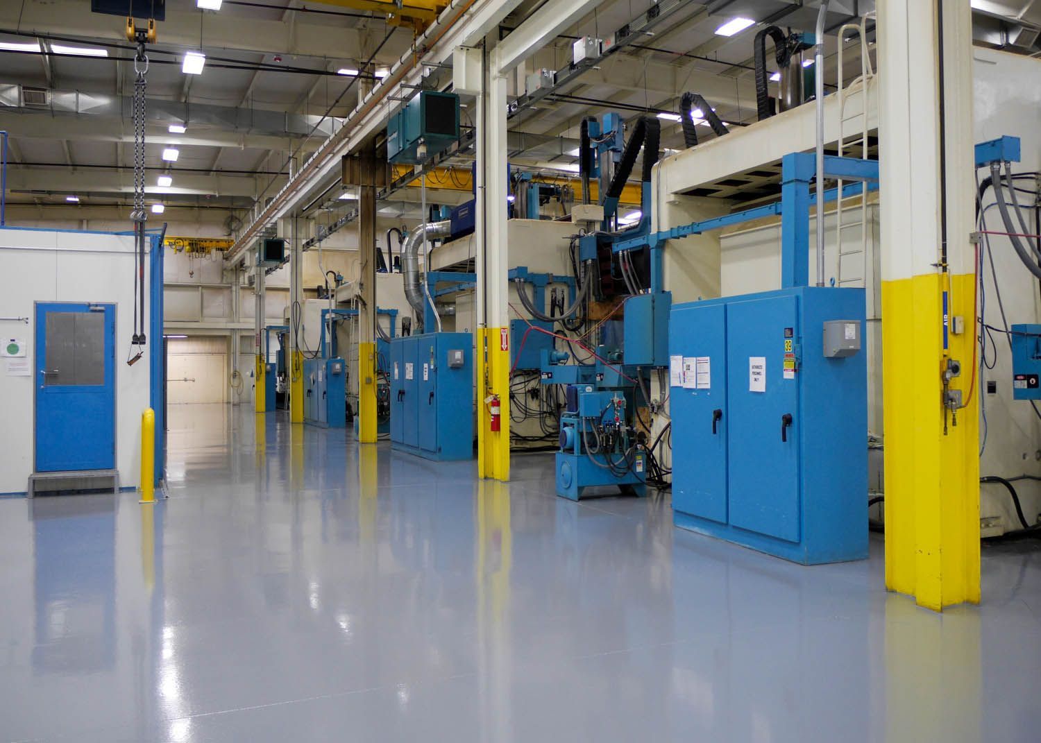 Empty industrial factory floor with blue machinery and yellow support columns