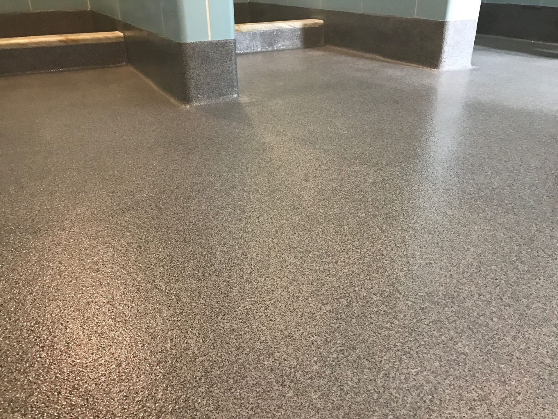 Empty indoor hallway with speckled brown floor and light green walls.