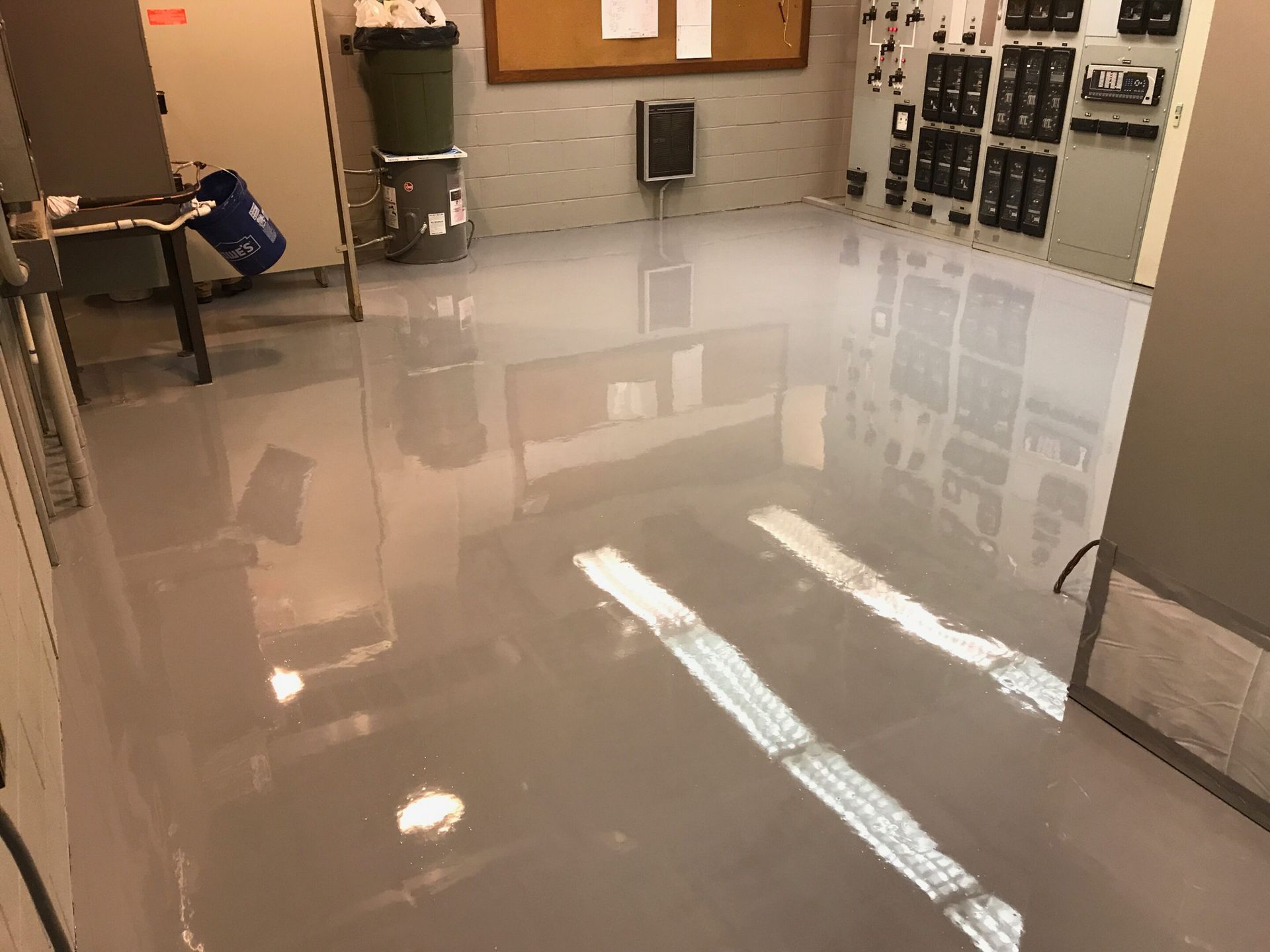 Shiny flooded room with reflections, cabinets, and wall-mounted electrical panels.