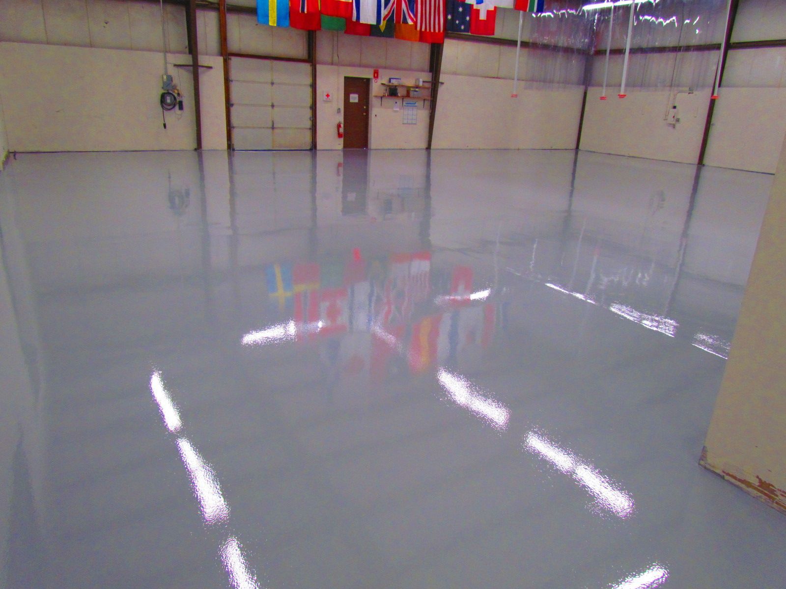 Empty indoor ice rink with a glossy, freshly resurfaced ice surface and hanging flags overhead