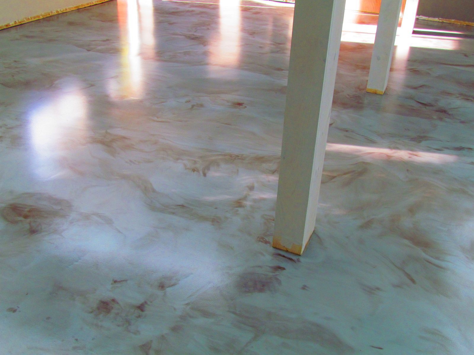 Sunlit concrete floor with white support columns and reflective patches inside a building