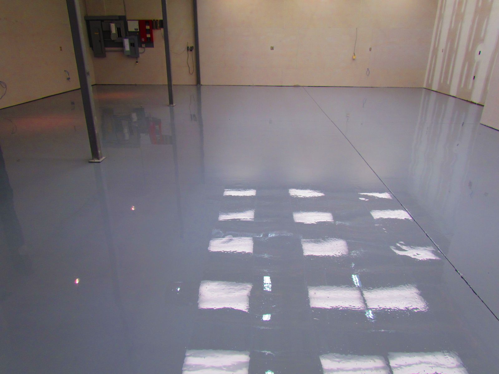 Empty glossy room with a shiny gray floor reflecting light from windows.