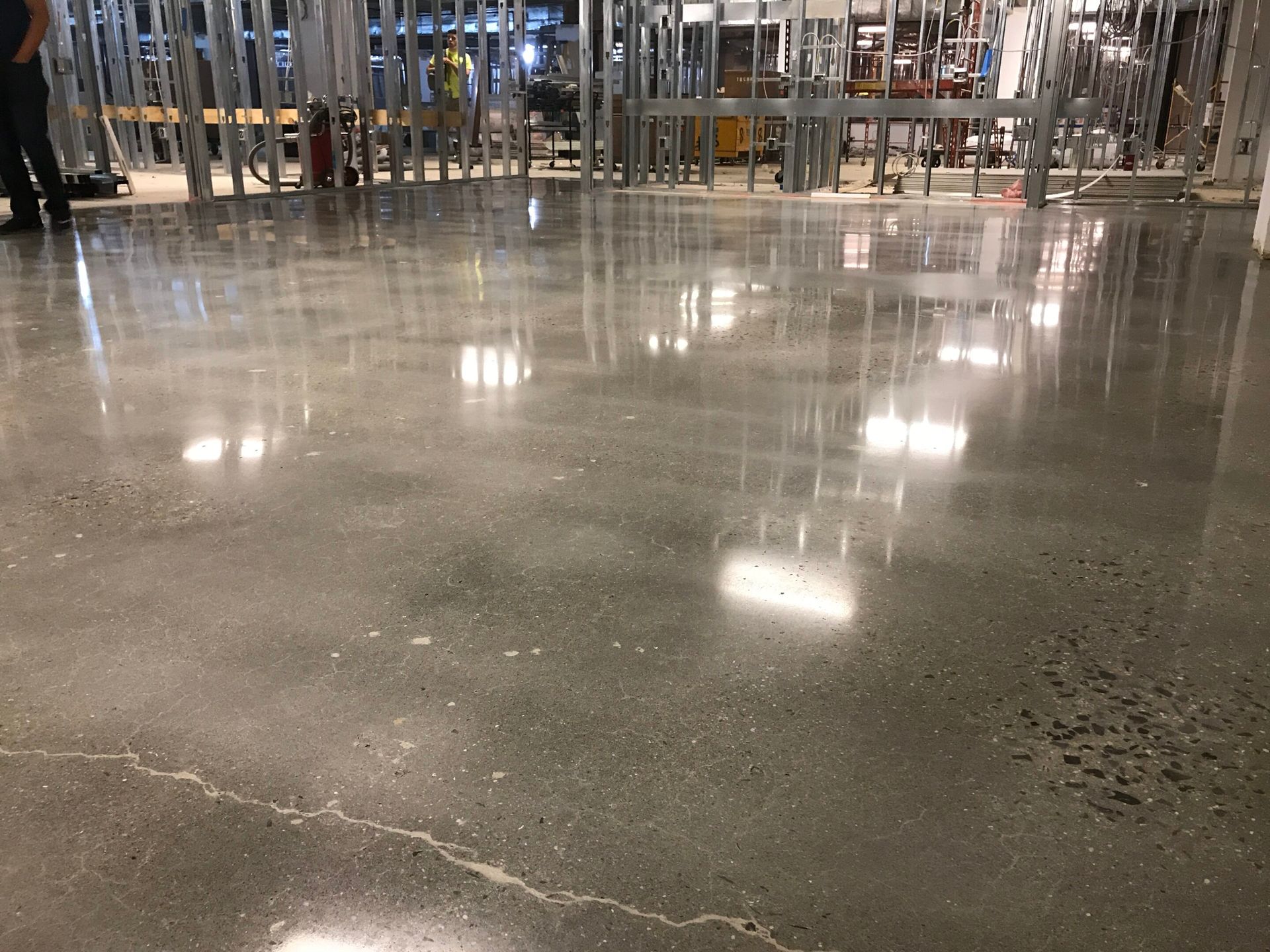 Shiny concrete floor in a warehouse-like store with shelves and lights reflected in the polished surface