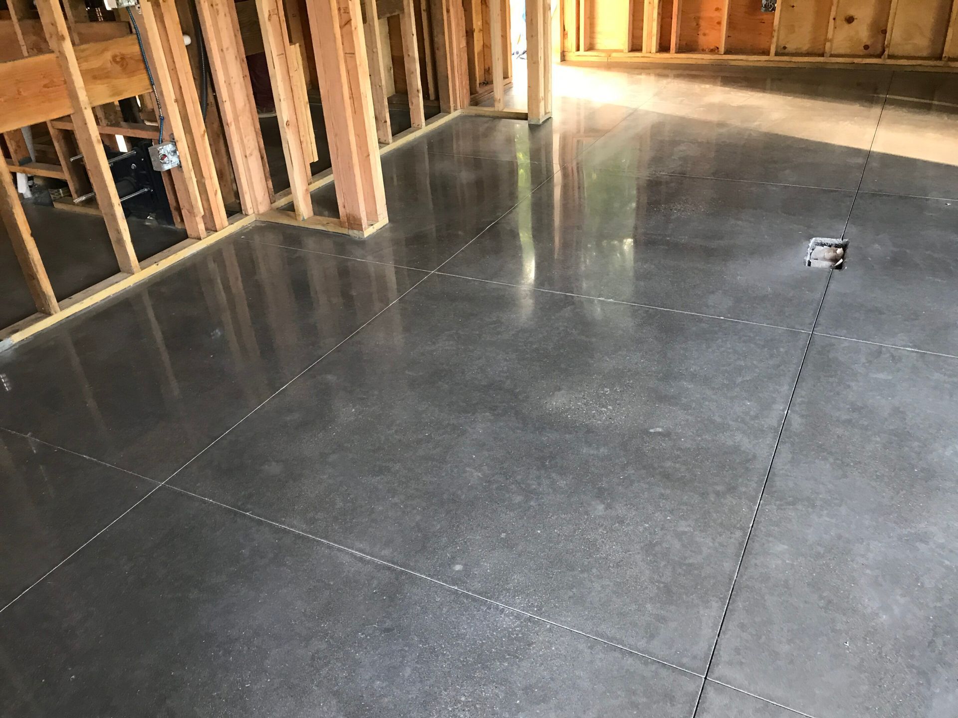 Unfinished basement with a smooth concrete floor and exposed wooden wall framing.