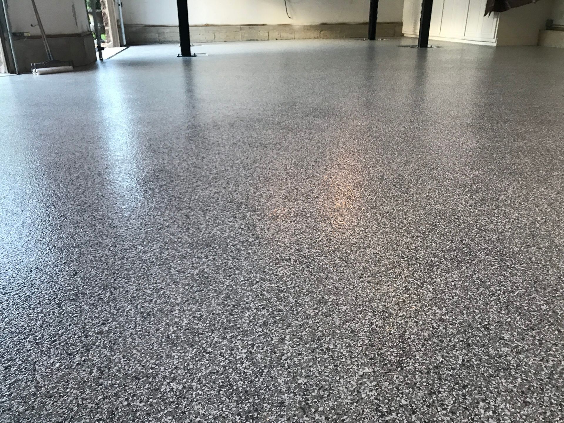 Speckled gray epoxy floor in an empty industrial room with windows and black support columns