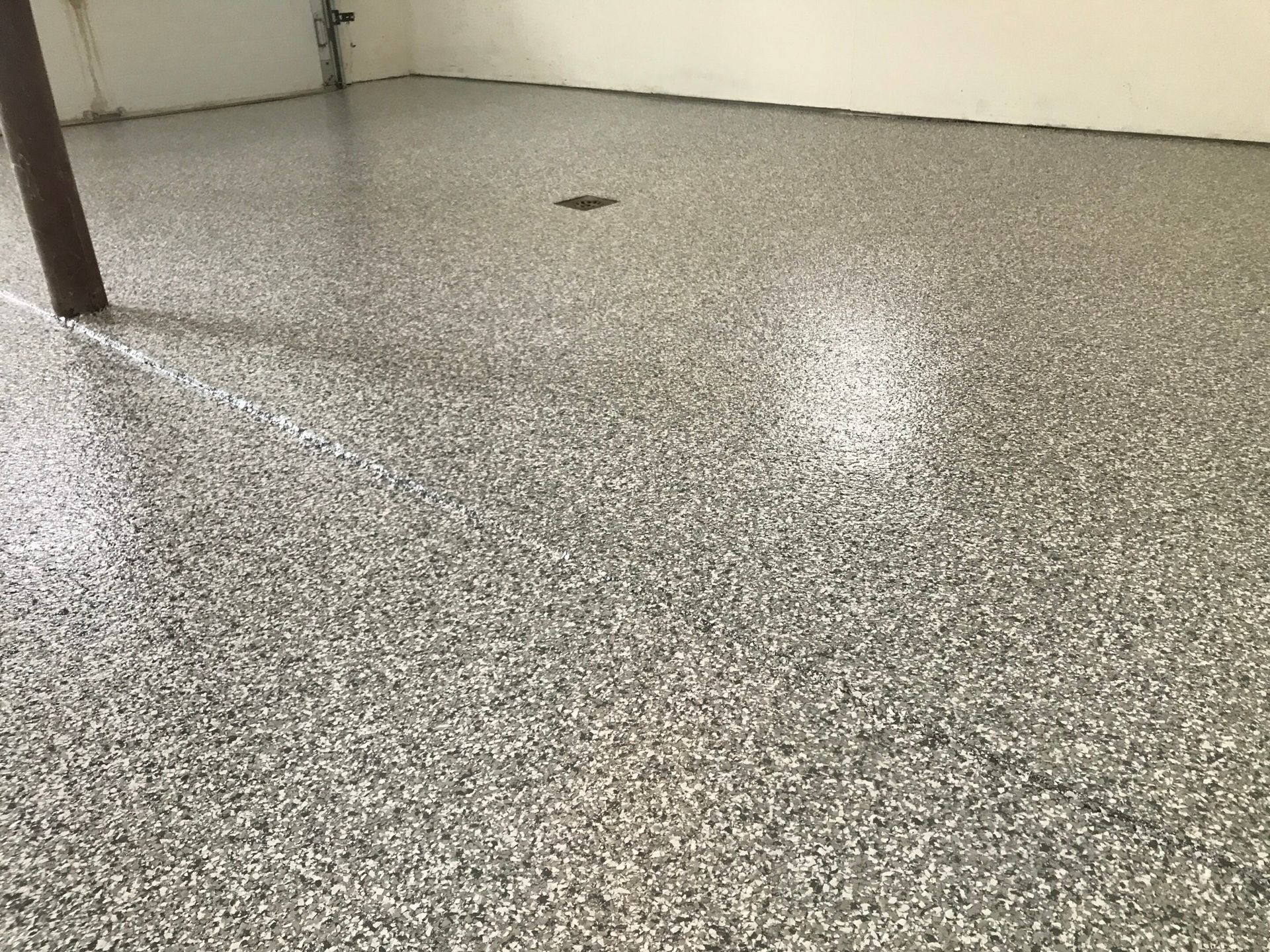 Empty speckled gray floor in a room with white walls and a table leg.