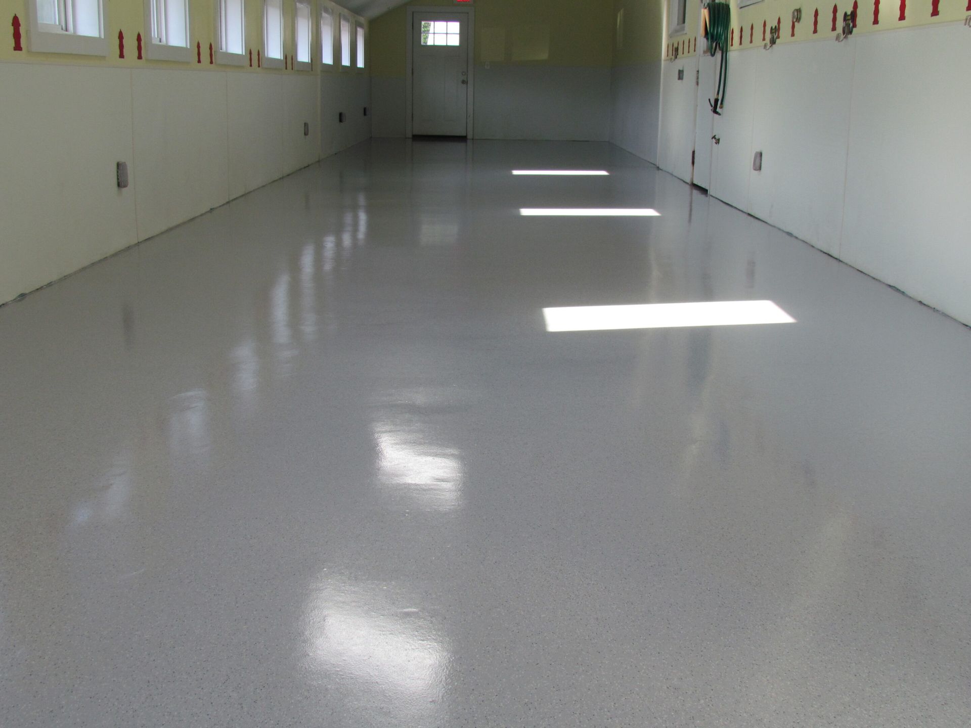 Empty white hallway with glossy floor and sunlight streaming through high windows