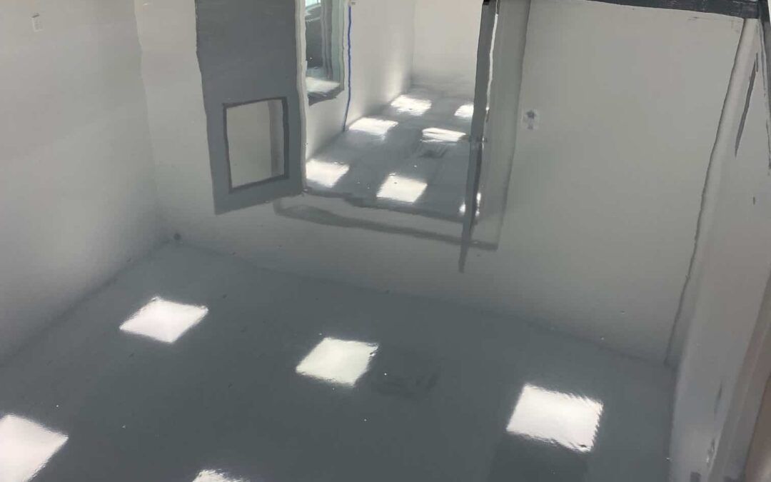 Sparse white room with sunlight from windows casting square light patches on the floor.
