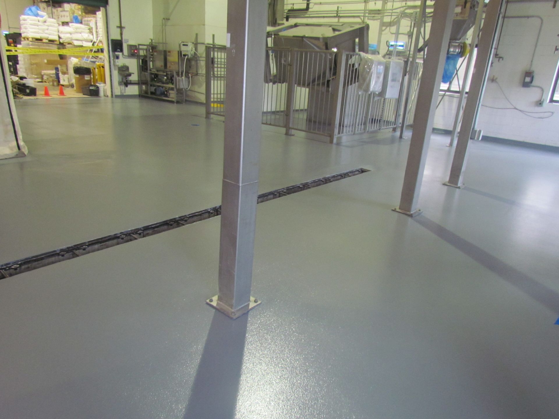 Empty industrial room with concrete floor, metal equipment, and a central support column