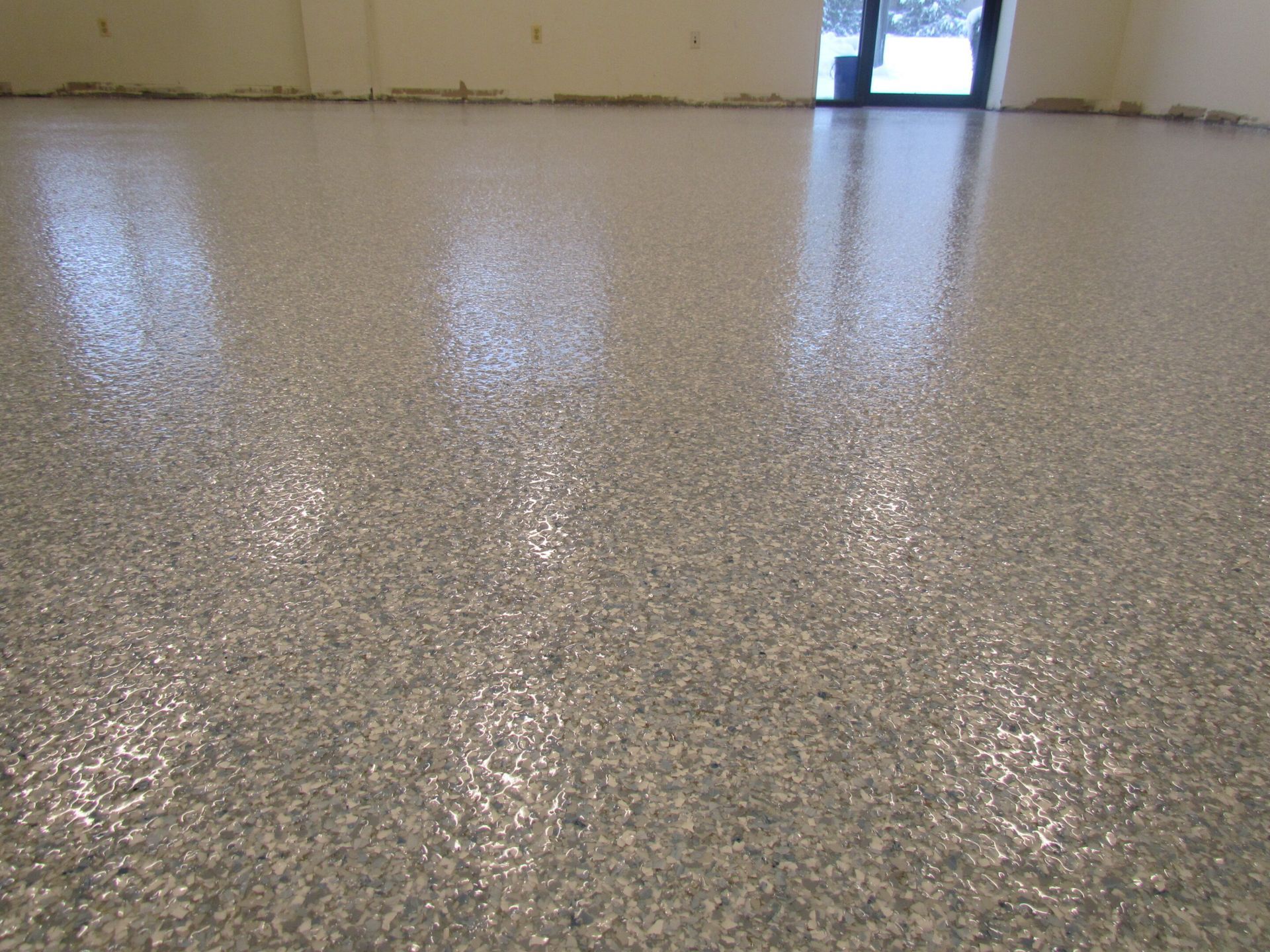 Empty speckled epoxy floor in an indoor room with a doorway in the distance