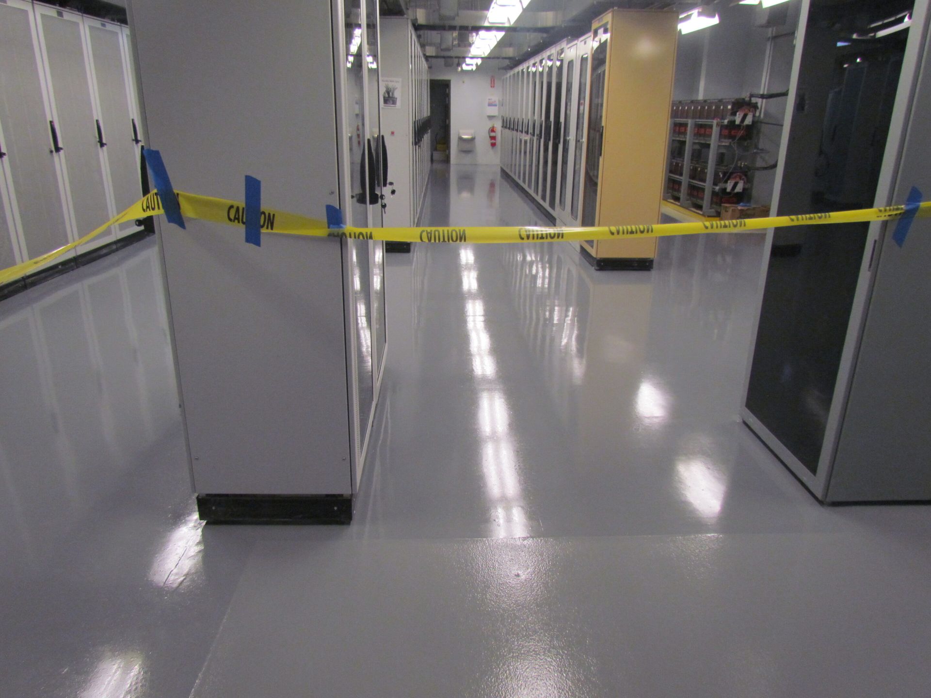 Yellow caution tape blocking a glossy hallway in an industrial facility