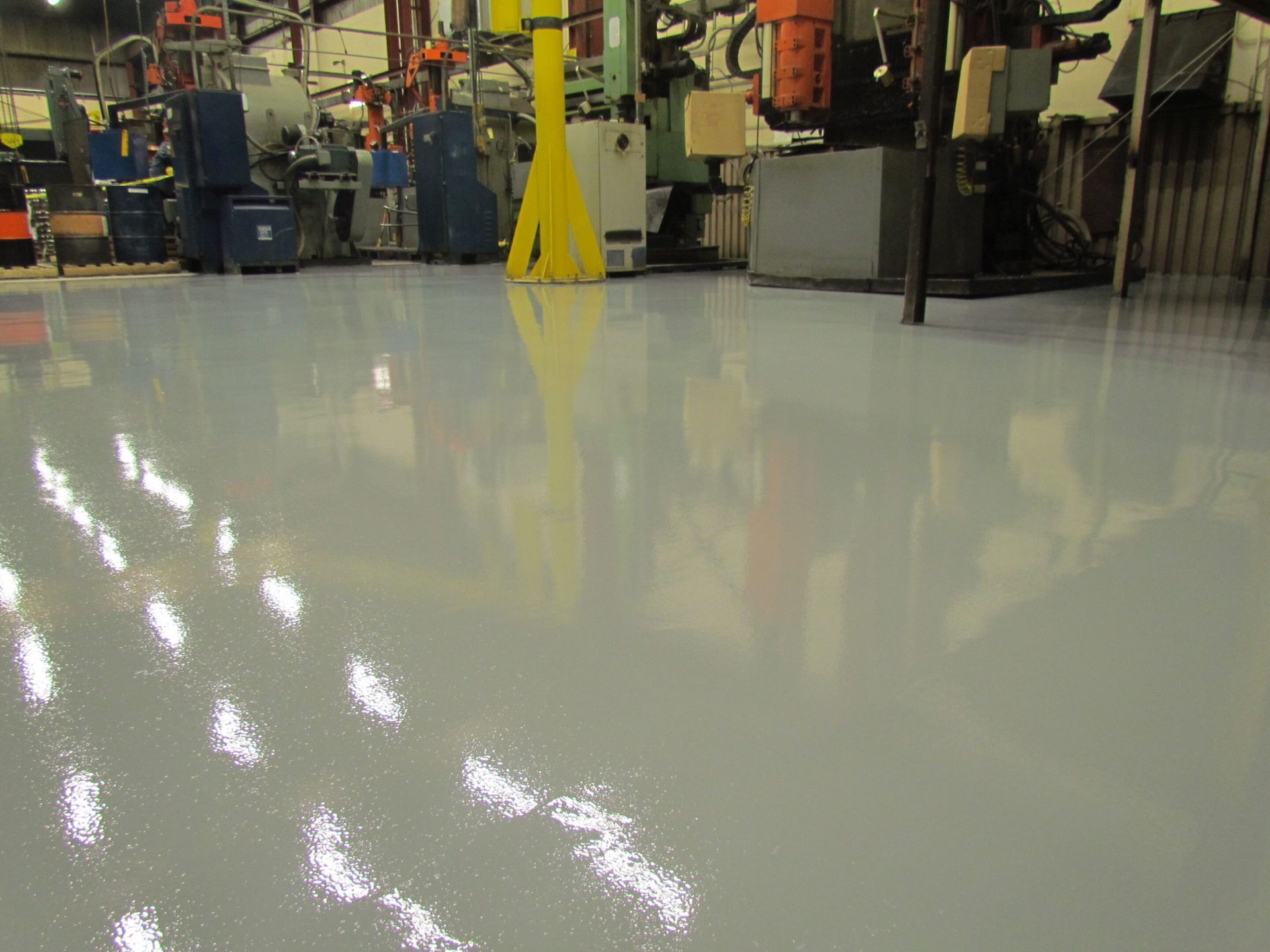 Shiny white factory floor with machinery and a yellow caution sign in the background