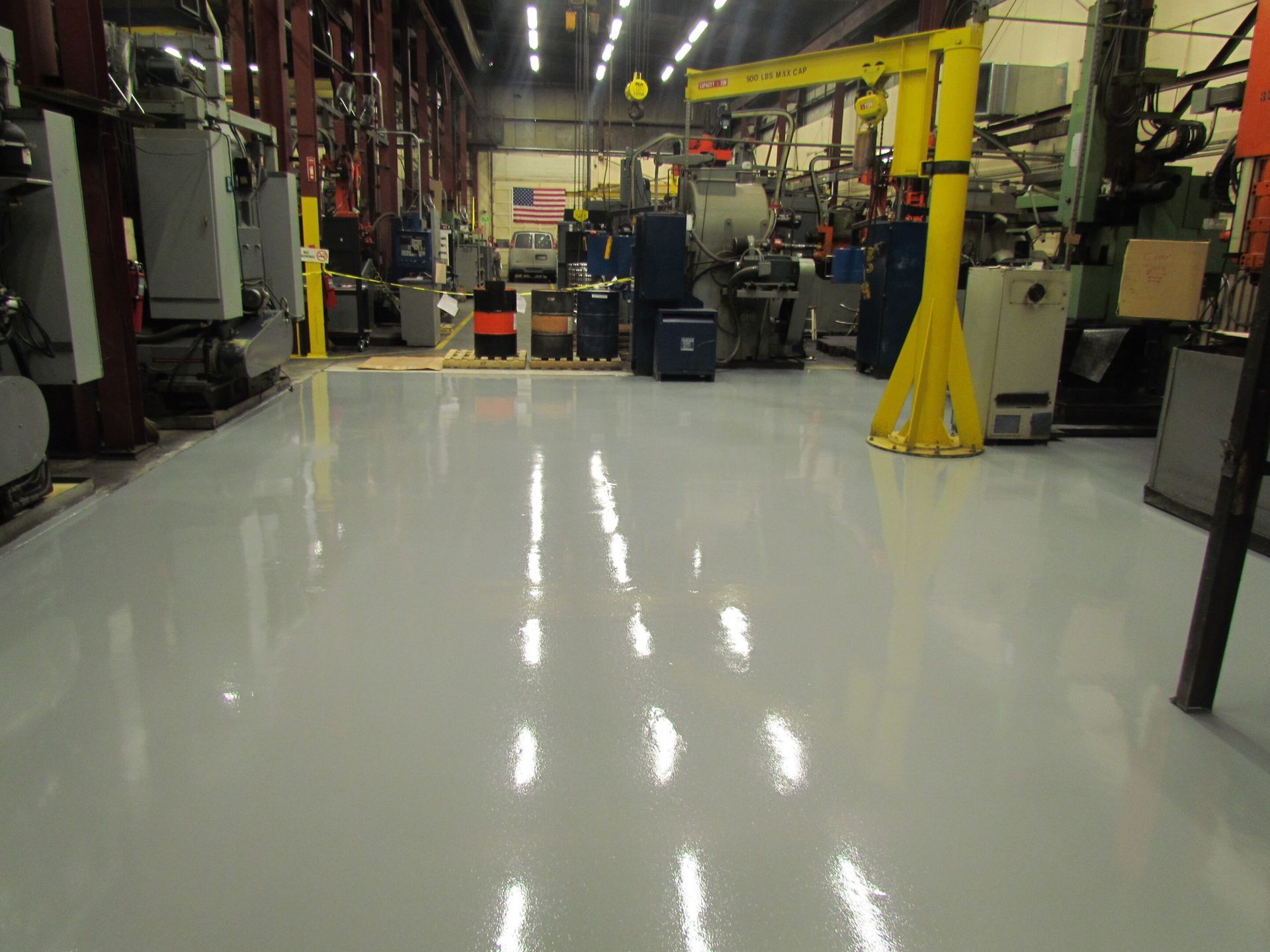Shiny white factory floor in a large industrial workshop with machinery and equipment around it