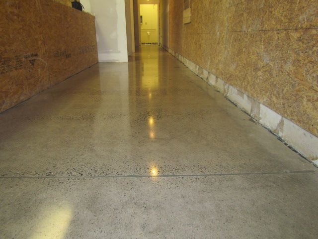 Empty polished hallway with tan walls and a bright doorway at the end