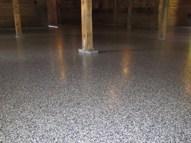 Polished speckled concrete floor in a wooden basement or crawlspace with support posts