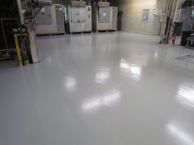 Empty industrial room with shiny gray floor and machinery along the walls
